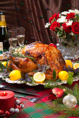 Garnished roast turkey on Christmas-decorated table with candles and flutes of champagneの写真素材