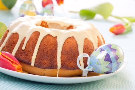 Easter cake with lemon icing, decorated with painted eggs and fresh tulips