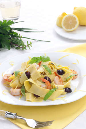 Shrimp lemon pepper Pappardelle pasta with fresh basil, and black olives.の写真素材