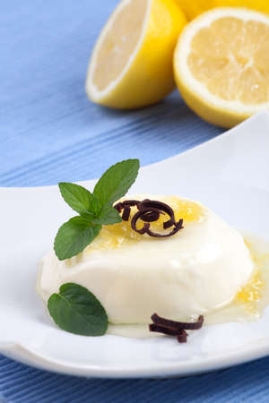 Closeup of Vanilla Panna Cotta Dessert garnished with lemon jam, chocolate shavings, and fresh mint.の写真素材