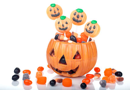 Halloween candy scattered around and in a pumpkin shaped bowlの写真素材