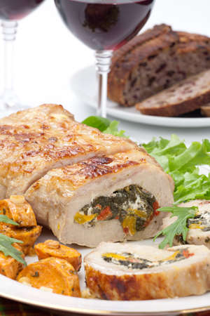 Feta-, spinach-, and bell pepper - stuffed pork tenderloin roulade garnished with sweet potato and green salad.の写真素材