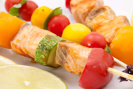 Closeup of grilled salmon and vegetable skewers with fresh tarragon and green saladの写真素材