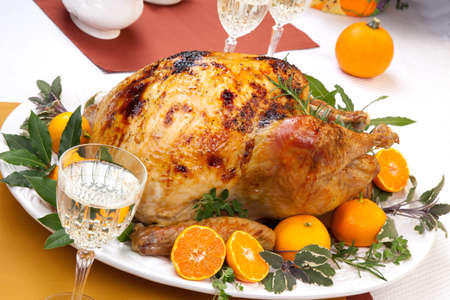 Garnished citrus glazed roasted turkey on holiday table, pumpkins, flowers, and white wineの写真素材