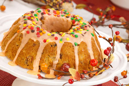 Fall cake with autumn leaves sprinkles over citrus icing, decorated with pumpkins and Indian cornの写真素材