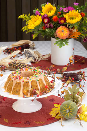 Fall cake with autumn leaves sprinkles over citrus icing, decorated with pumpkins and Indian cornの写真素材