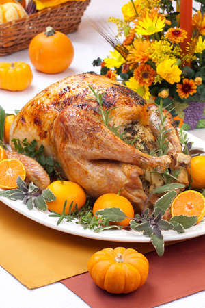 Garnished citrus glazed roasted turkey on holiday table, pumpkins, flowers, and white wineの写真素材