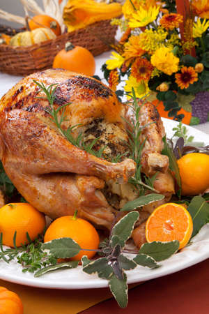 Garnished citrus glazed roasted turkey on holiday table, pumpkins, flowers, and white wineの写真素材