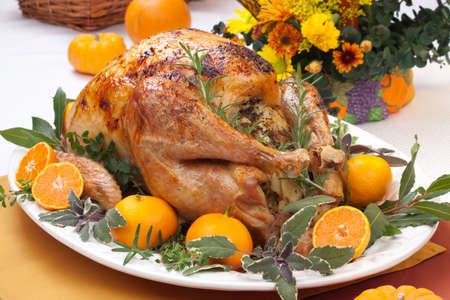 Garnished citrus glazed roasted turkey on holiday table, pumpkins, flowers, and white wineの写真素材