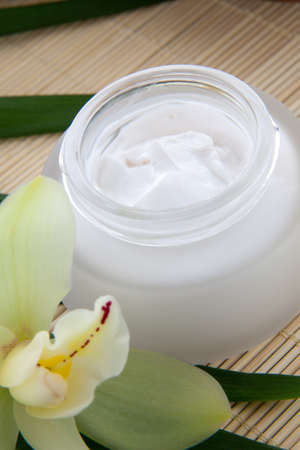 White Cymbidium orchid flower and jar of moisturizing face cream for spa treatment.の写真素材