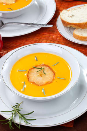 Closeup of bowls of hot delicious pumpkin soup with roasted apples, and rosemary.の写真素材