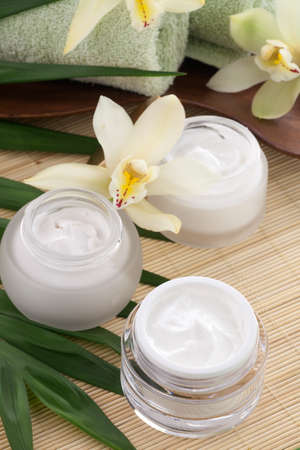 White Cymbidium orchid flower and jar of moisturizing face cream for spa treatment.の写真素材