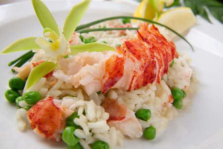Lobster and green pea Risotto garnished with chives, lemon, and orchid flower の写真素材
