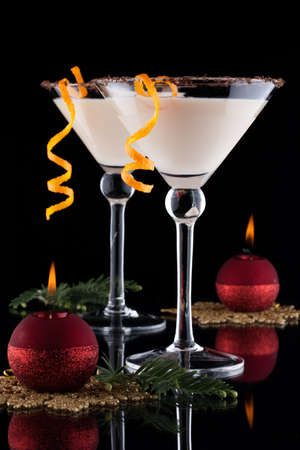 Closeup of Orange Chocolate Dream - festive Christmas cocktail with candles and ornamets over black background  Orange twist and chocolate rim  Holiday cocktails series の写真素材