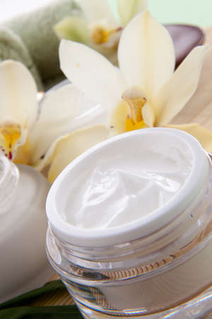 White Cymbidium orchid flower and jar of moisturizing face cream for spa treatment の写真素材