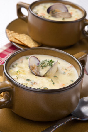 Bowls of hot delicious clam chowder garnished with fresh thyme, and multy grain crackers