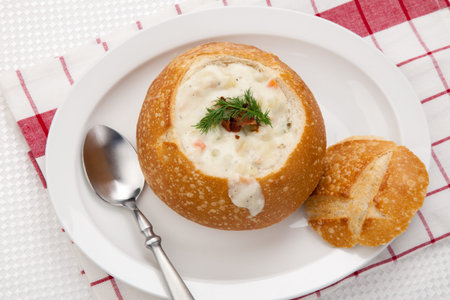 Sourdough bun of delicious hot clam chowder garnished with bacon, and dill の写真素材