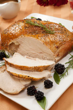Carved Rosemary-basil rub roasted turkey breast garnished with grapes, blackberies, and fresh basil, and rosemary in fall themed surrounding の写真素材