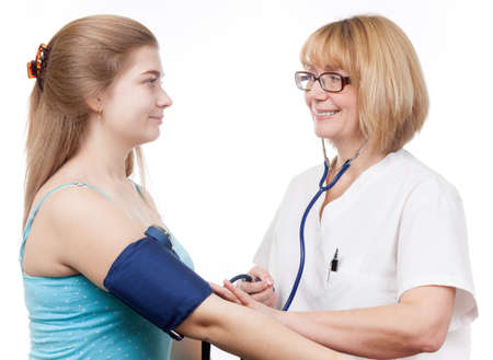 Nurse is checking blood pressure on teenage girl during a medical office visit の写真素材