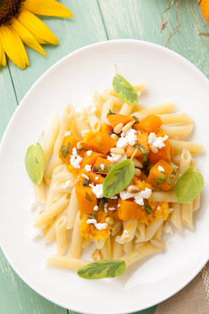 Healthy whole grain Penne  tube-shaped  pasta with pumpkin, goat cheese, sage, and pine nuts の写真素材