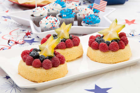 Tray of fresh Angel food fruit cakes with raspberry, blueberry, and star fruit  Muffins on 4th of July in patriotic theme in background の写真素材