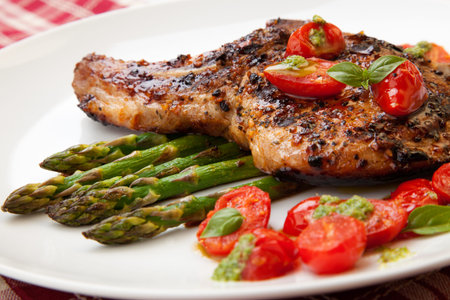 Grilled pork chops and asparagus  Served with fried grape tomatoes salad and pesto sauce の写真素材