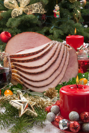 Christmas dinning table with glazed roasted ham with tomatoes, herbs, and kumquats. の写真素材