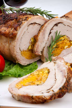 Dried apricots, pistachios, and rosemary staffed pork loin roulade served with salad, tomatoes and glass of red wine.の写真素材
