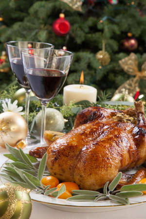 Citrus glazed roasted duck stuffed with rice, garnished with apples, kumquats, and sage. Christmas decorated setting.の写真素材