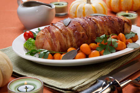 Delicious bacon-wrapped turkey breast roulade garnished with Brussels sprouts, tomatoes, and Parisian carrots.の写真素材