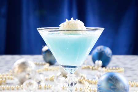 Closeup of Winter Wonderland Cocktail, garnished with coconut vanilla ice cream ball on Christmas decorated holiday table with Christmas ornaments. Holiday cocktails series.の写真素材