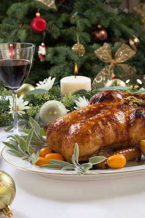 Citrus glazed roasted duck stuffed with rice, garnished with apples, kumquats, and sage. Christmas decorated setting.の写真素材