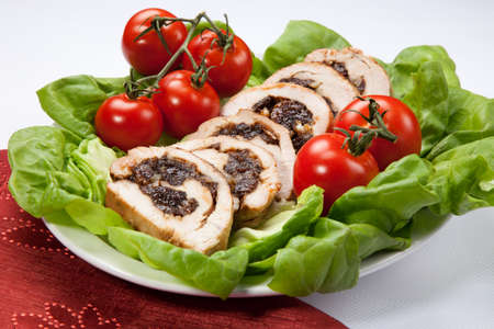Delicious turkey breast roulade cut in slices stuffed with prunes and almond. Garnished with butter lettuce and tomatoes on vines.の写真素材