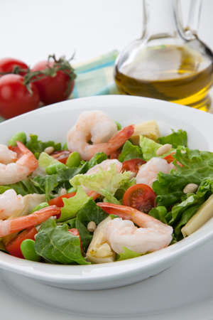 Plate of Italian shrimp salad with shrimp, tomatoes, artishocke hearts, Romane lettuce leaves, fava beans, and pine nuts. Olive oil.の写真素材