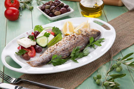 Mediterranean style organic roasted whole sea bass, garnished with Greek salad.の写真素材