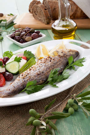Mediterranean style organic roasted whole sea bass, garnished with Greek salad.の写真素材