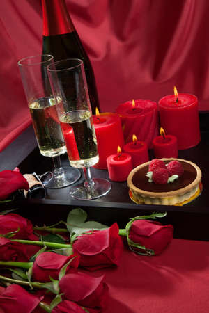 Celebration tray for Valentines Day - Champagne, chocolate raspberry cake, candles, and red roses.の写真素材