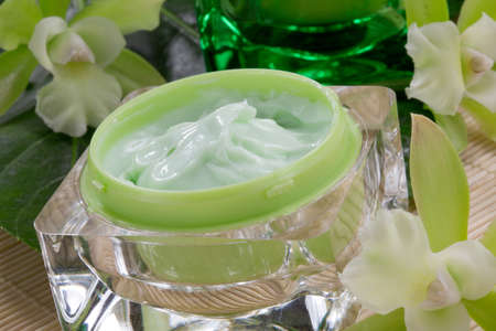 Closeup gorgeous blooming green colored Cattleyas orchid flowers and jars of cosmetics cream.の写真素材