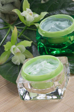 Closeup gorgeous blooming green colored Cattleyas orchid flowers and jars of cosmetics cream.の写真素材