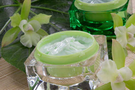 Closeup gorgeous blooming green colored Cattleyas orchid flowers and jars of cosmetics cream.の写真素材