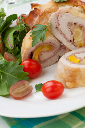 Tasty chicken prosciutto roulade stuffed with cheese and pineapple, served with baby kale, grapes, and cherry tomatoes salad.の写真素材