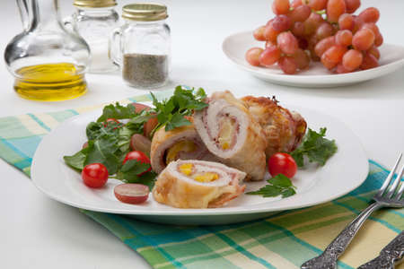 Tasty chicken prosciutto roulade stuffed with cheese and pineapple, served with baby kale, grapes, and cherry tomatoes salad.の写真素材