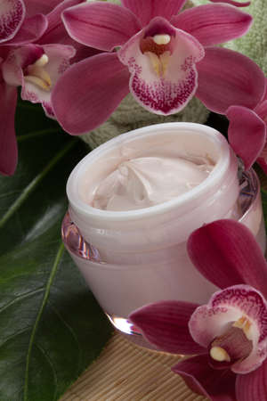 Dark pink blooming Cymbidium orchid flowers and moisturizing face cream for everyday.の写真素材
