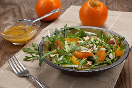 Closeup of a plate of arugula salad with mandarins, oranges, beans sprouts, and sliced almonds served with mandarin vinaigrette for healthy lunch.の写真素材