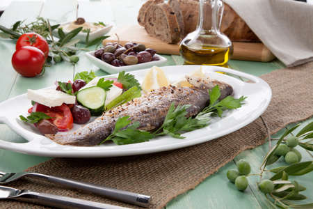 Mediterranean style organic roasted whole sea bass, garnished with Greek salad.の写真素材