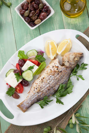 Mediterranean style organic roasted whole sea bass, garnished with Greek salad.の写真素材