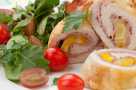 Tasty chicken prosciutto roulade stuffed with cheese and pineapple served with baby kale grapes and cherry tomatoes salad.の写真素材