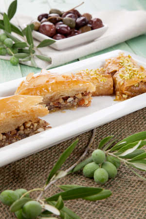 Mediterranean traditional pastries  Baklava  served with Greek style black olives on a wooden tableの写真素材