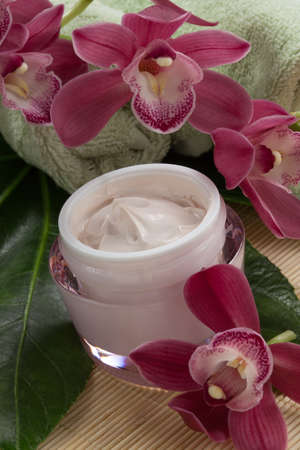 Dark pink blooming Cymbidium orchid flowers and moisturizing face cream for everyday.の写真素材