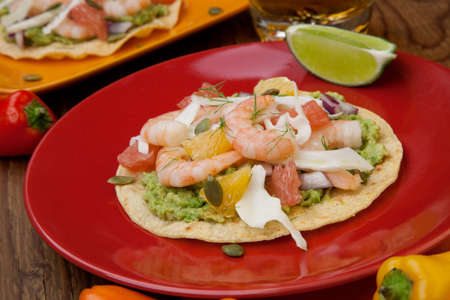 Two plates of shrimp ceviche tostadas with fennel and grapefruit beer garnished with mini bell pepper.の写真素材